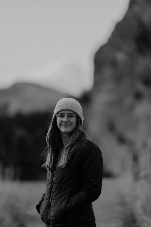 a girl wearing a hat in front of rocks