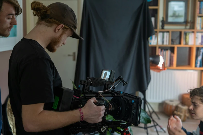 a young man standing next to a person with a camera