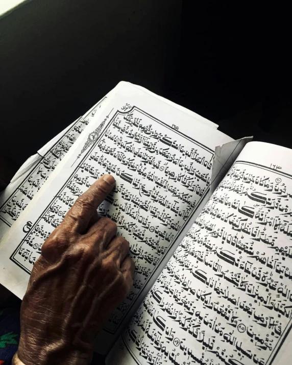 the hands of an old man are reading a book