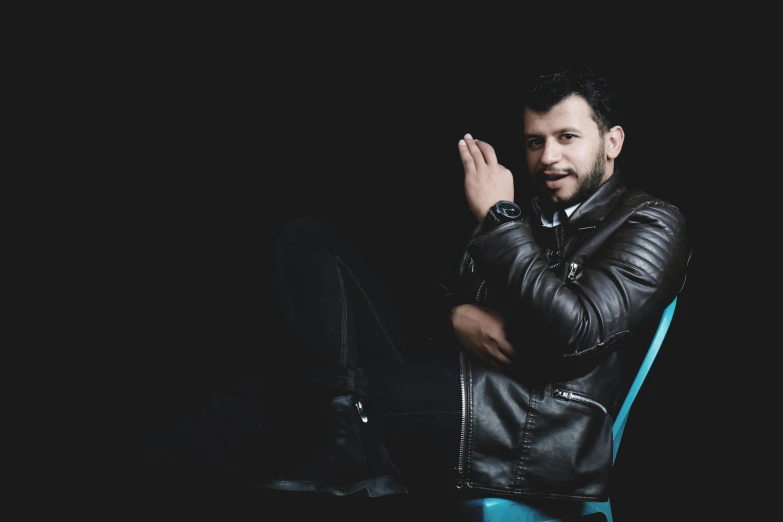 a man sitting on a chair with his arms crossed and a hand clasped, in front of him