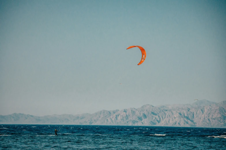 kite surfing in an open ocean next to a mountain range