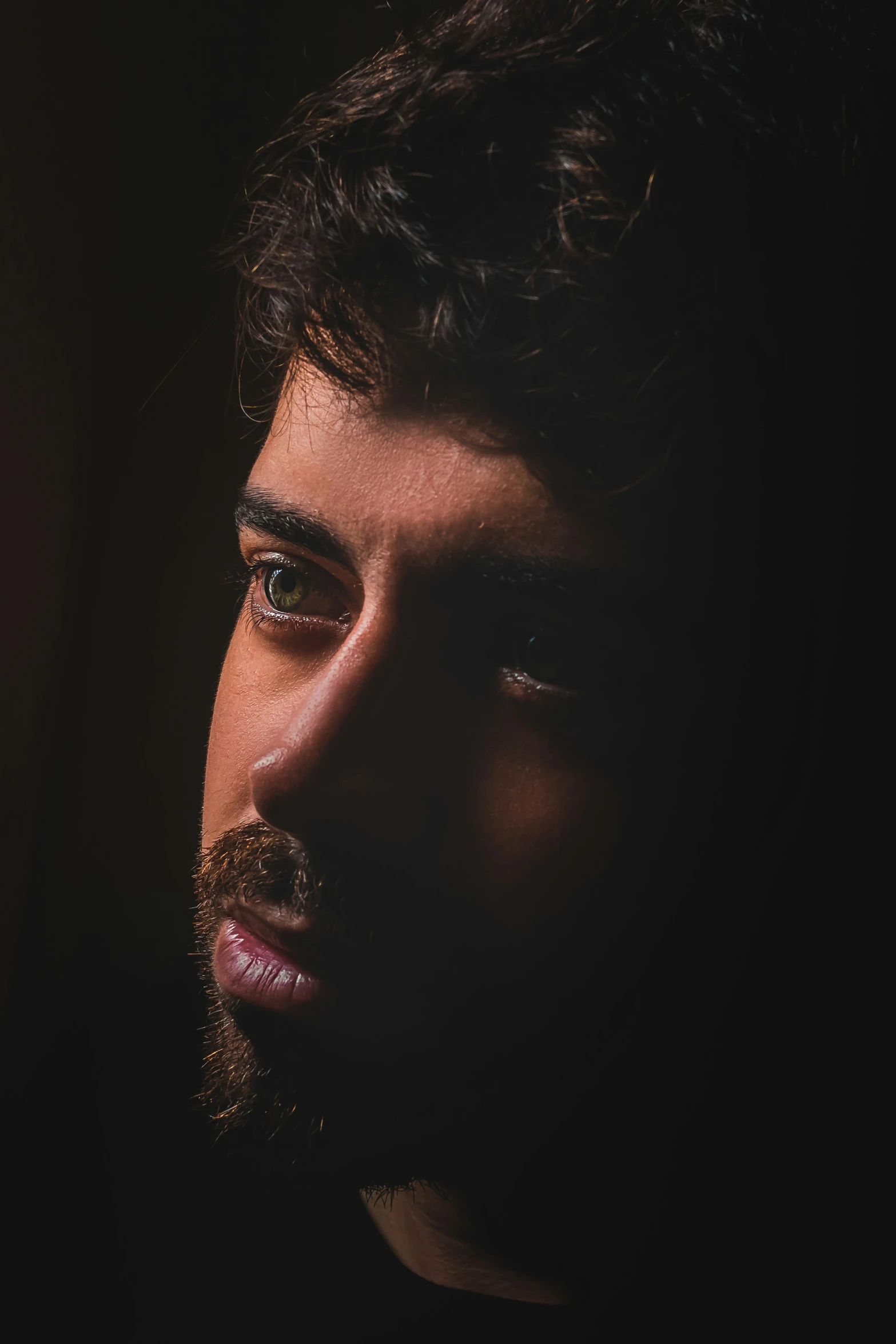 a bearded man in the dark with eye lashes open
