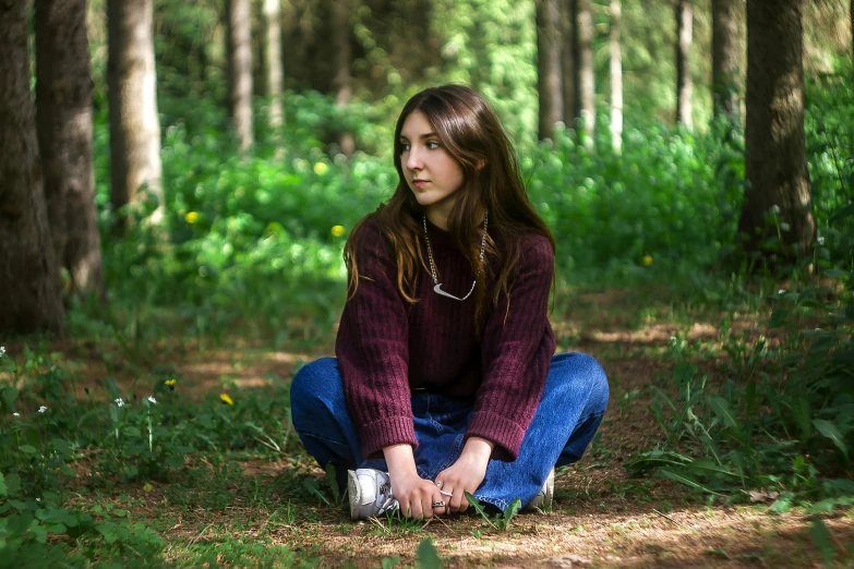 a girl is squatted in the woods