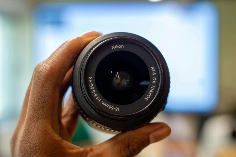 someone holding a camera lens up with their thumb