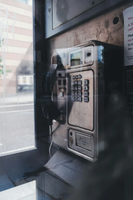 an old public phone sitting next to a street