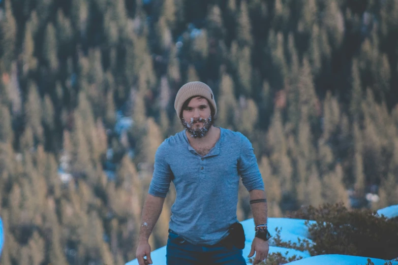 man in grey shirt and hat walking in snowy terrain