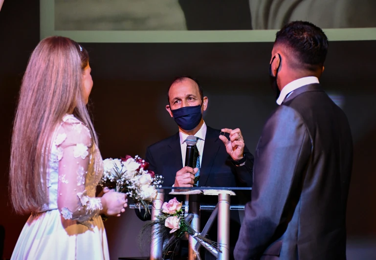 man wearing a face mask and holding hands while the woman stands near him