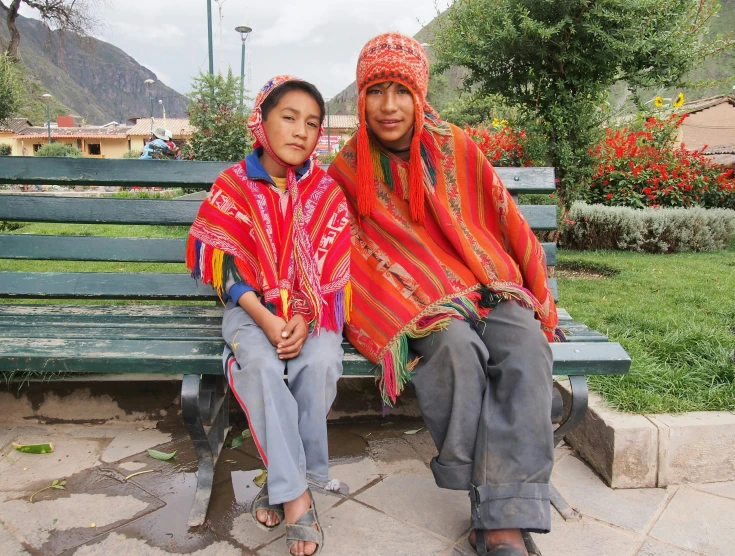 two people sitting on a bench in front of a field