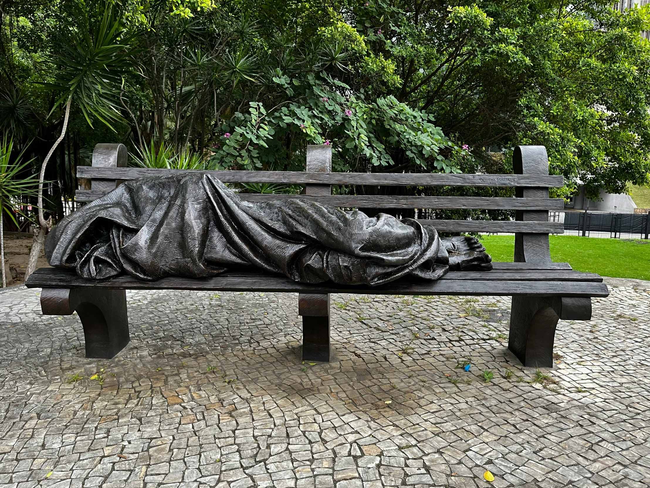 a covered park bench sitting on a stone floored area