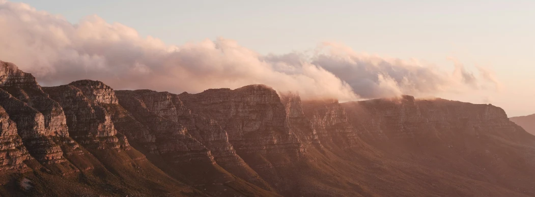 a mountain top with a lot of clouds above it