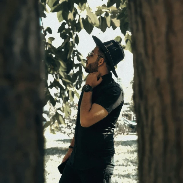 a man standing next to a tree talking on a cell phone