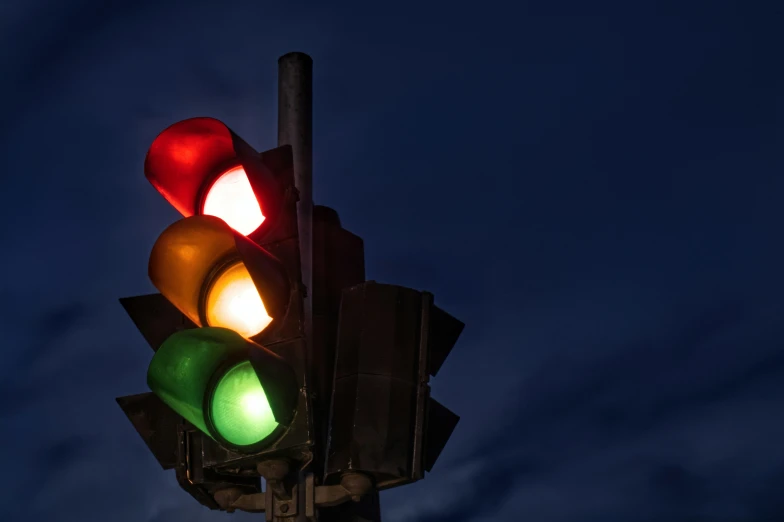 an illuminated traffic light sitting under a cloudy sky