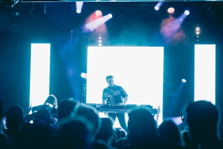 two djs are making tracks on stage while the crowd watches