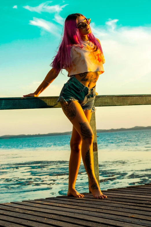 a woman with pink hair in bathing suit posing by a pier