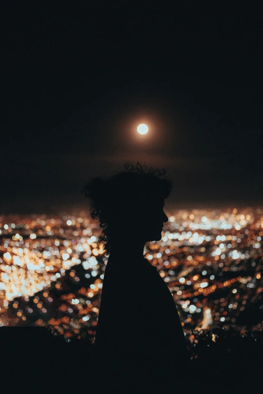 a person looking over a city lit up by the night