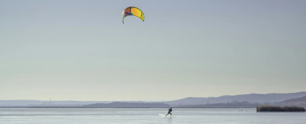 a man flying a kite with mountains in the distance