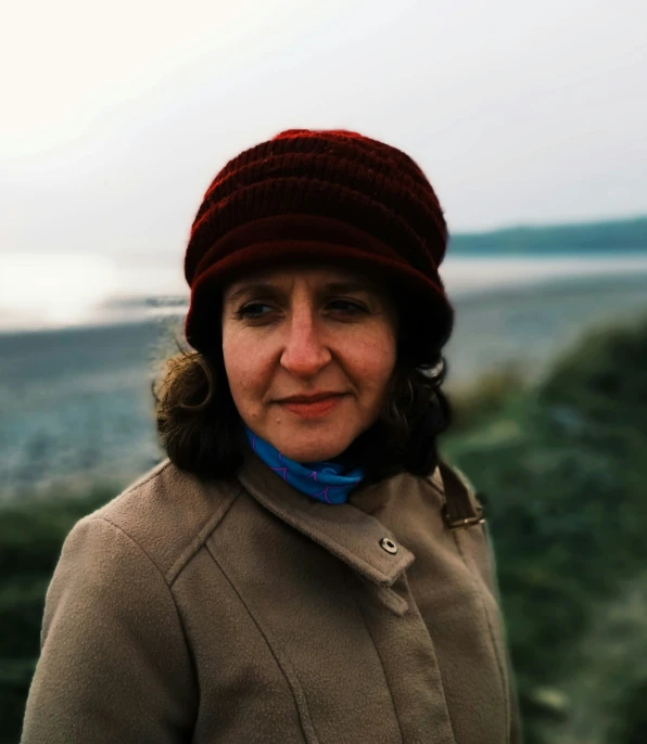 a woman in a red hat standing next to the water