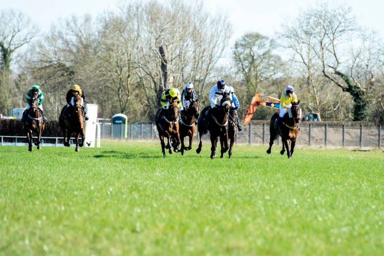 there are jockeys and horses in a race on a field