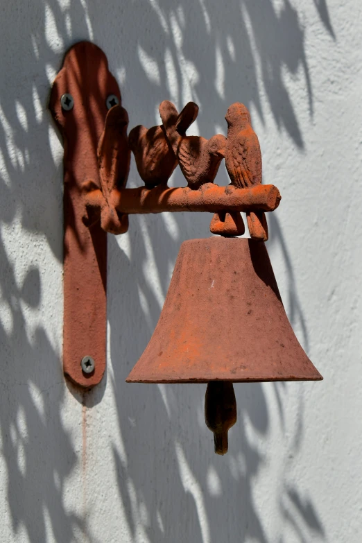 an orange bell hanging on a white wall