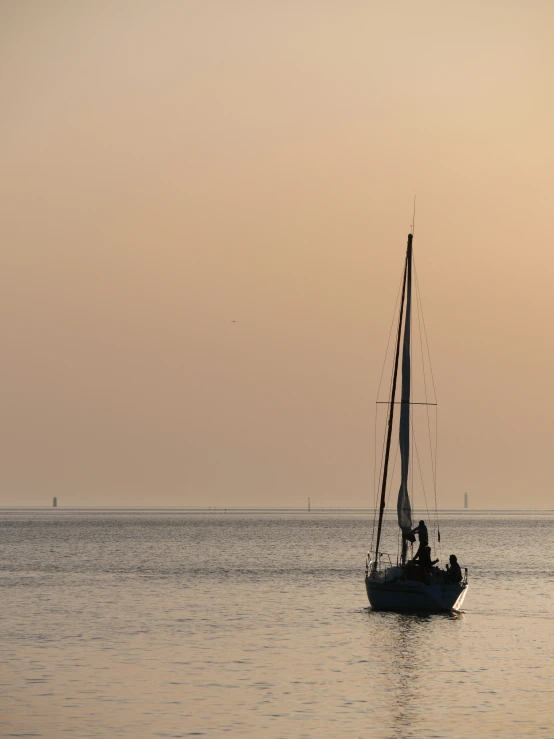 an old sailboat floating in the water with its sails down