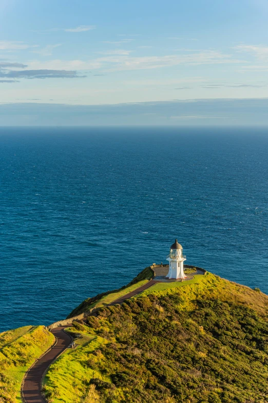 a lighthouse sits on a grassy island off the coast