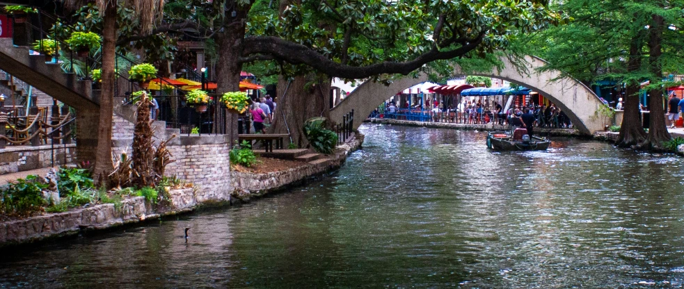 the water in a river has people on boats underneath the bridge