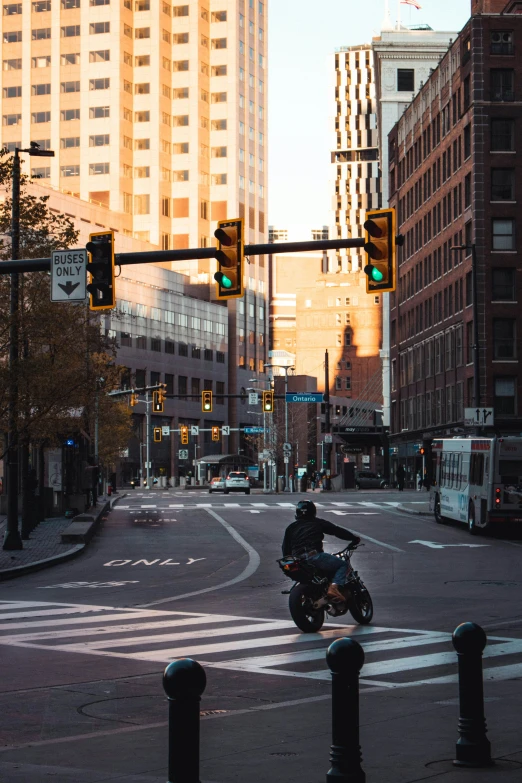 a motorcyclist rides in a traffic light while a city street is seen