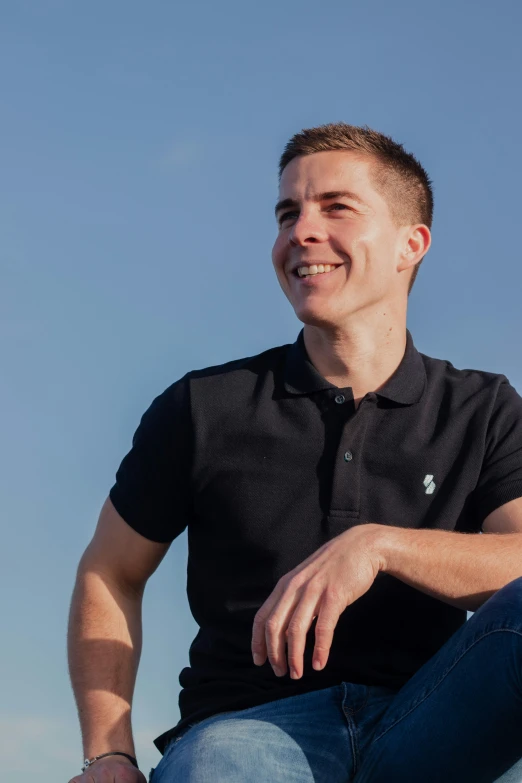 a man sits wearing a black shirt while looking into the distance