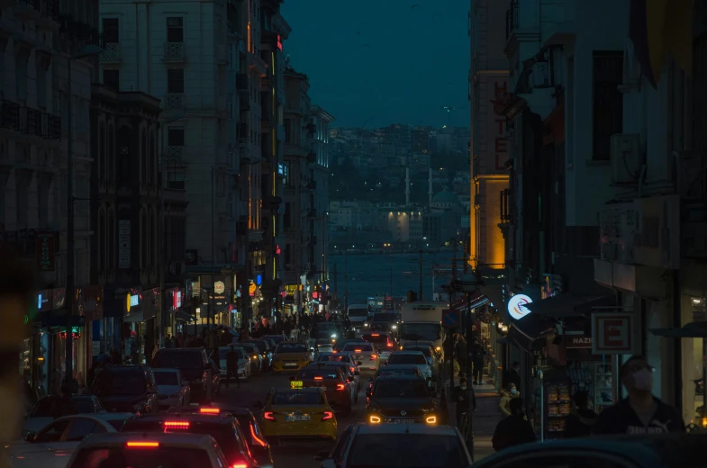 a city street with several cars driving down the middle of it at night