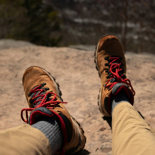 a man wearing brown sneakers on top of a mountain