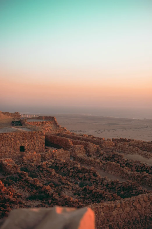 a sunset over the desert with ruins and water