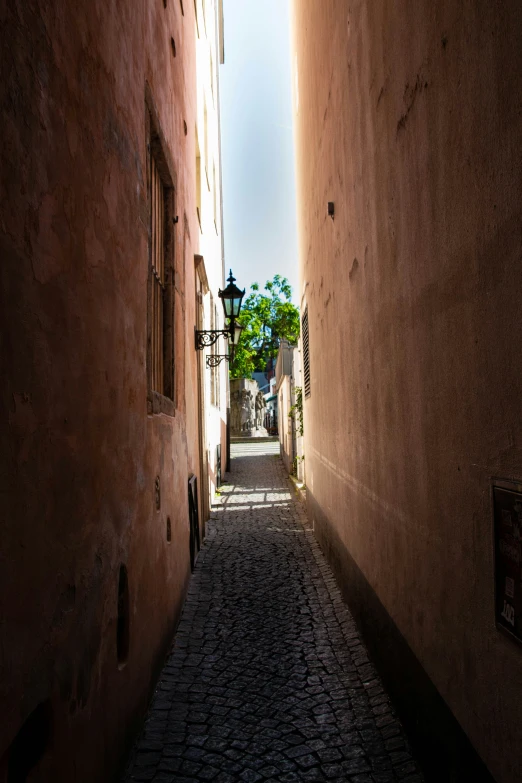 an empty cobbled alley leading to a street light