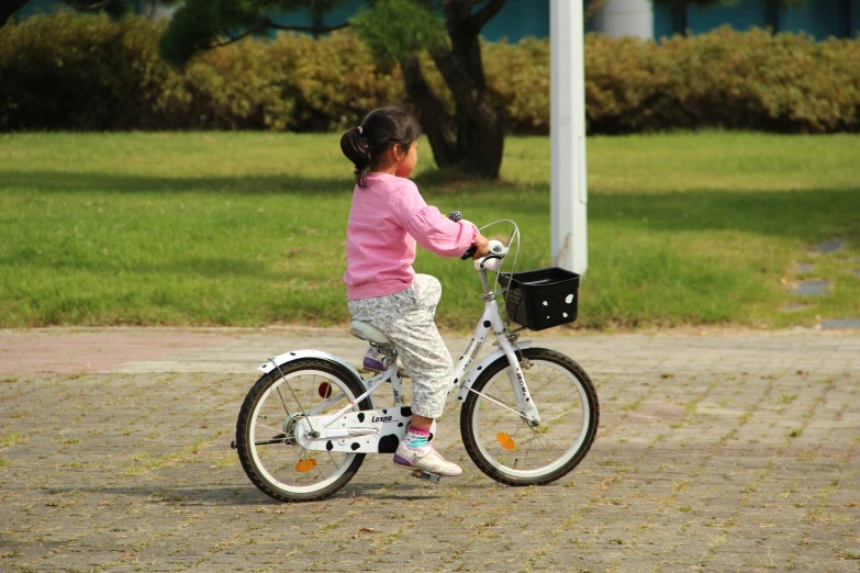 a little girl riding a little bike with basket