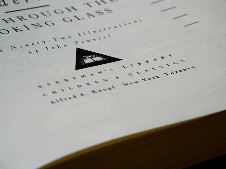 a close up of an open book with a paper and black triangle