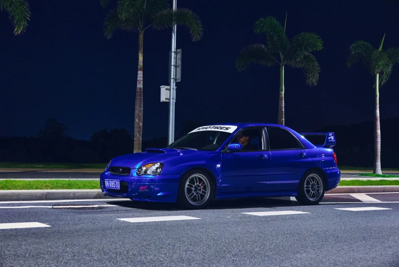 a blue subaru that is parked next to some palm trees