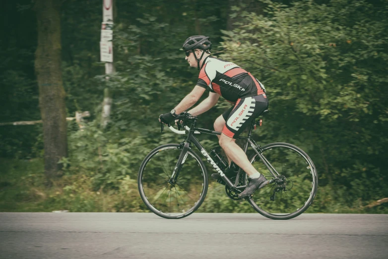 a man wearing a helmet on a bike rides down the road