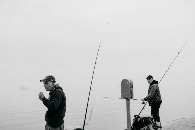men with fishing gear on a dock by water