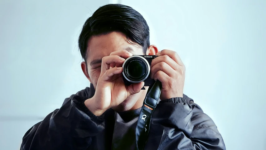 a man in a leather jacket is holding a camera and taking a picture