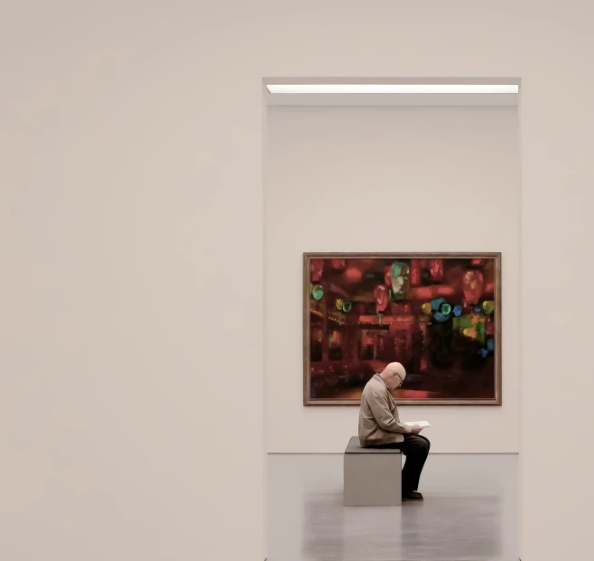 a man sitting on a bench in front of a painting