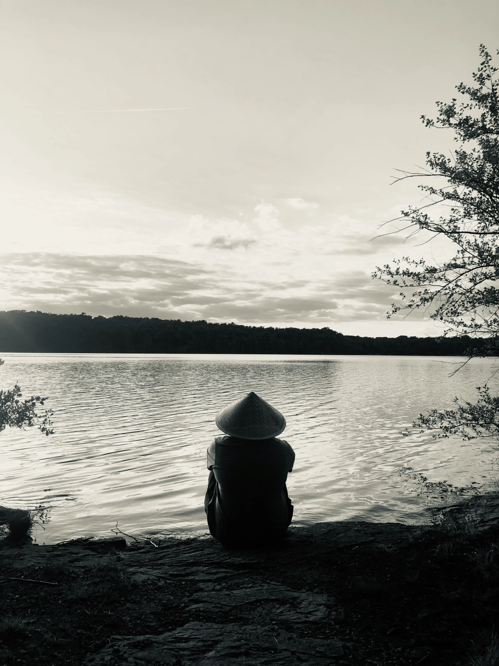 a person sitting near the water watching the sunset