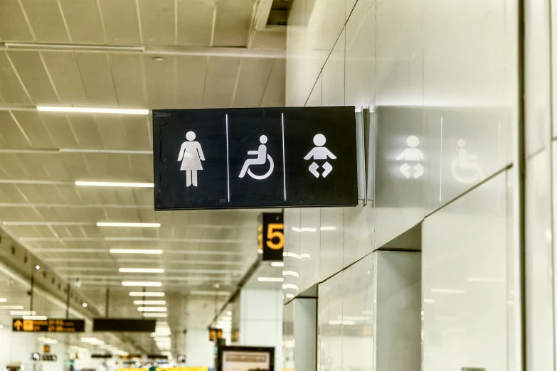 an airport lobby has three restroom signs above the elevators