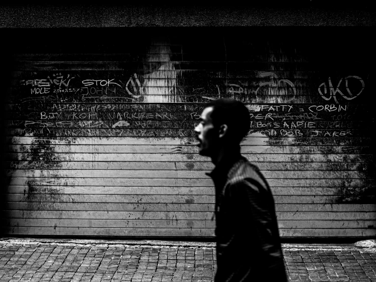 a man walks past graffiti sprayed on the walls of an alleyway