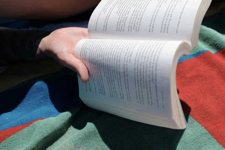 someone reading a book while laying down on a blanket