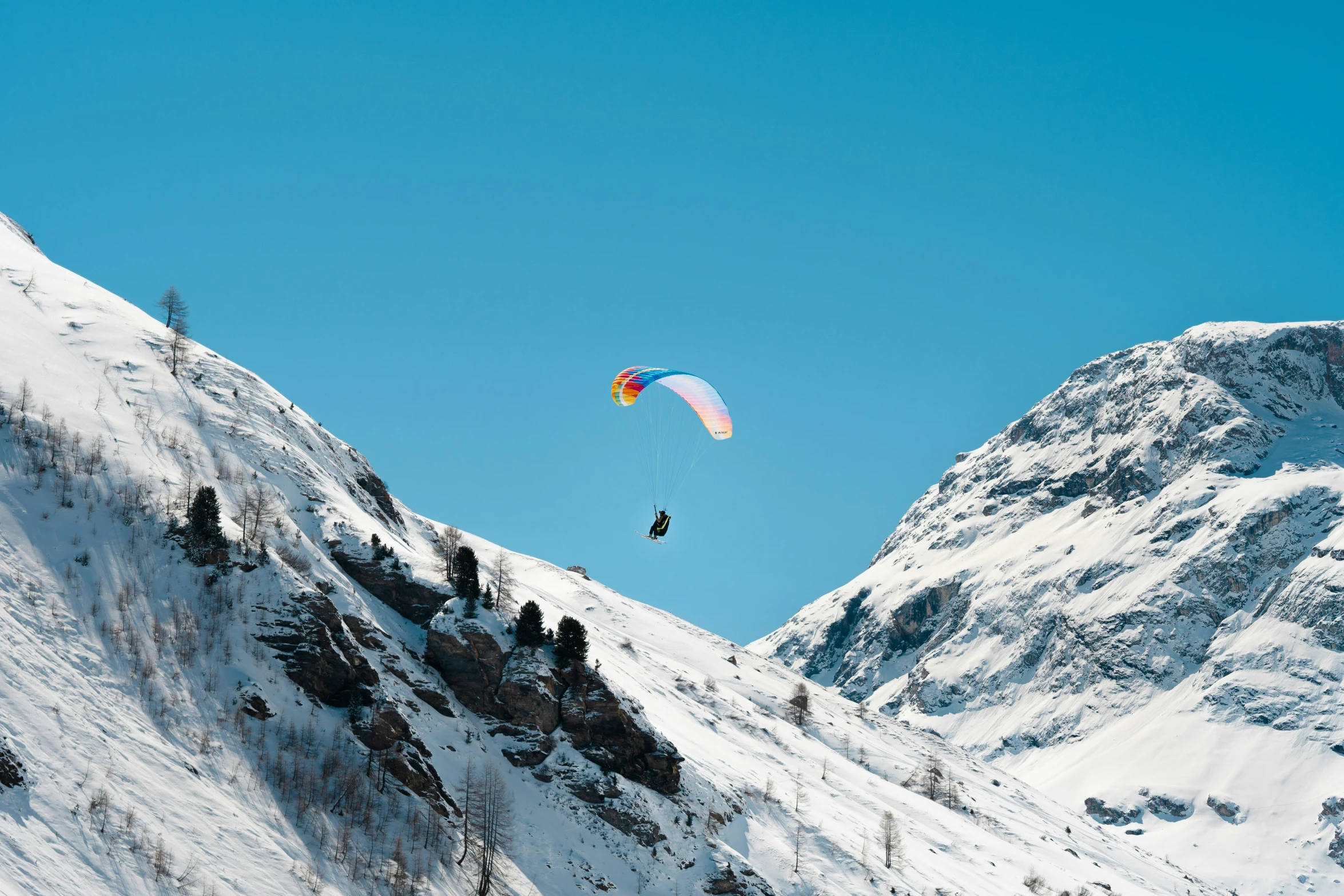 two people are parachute skiing in the snow