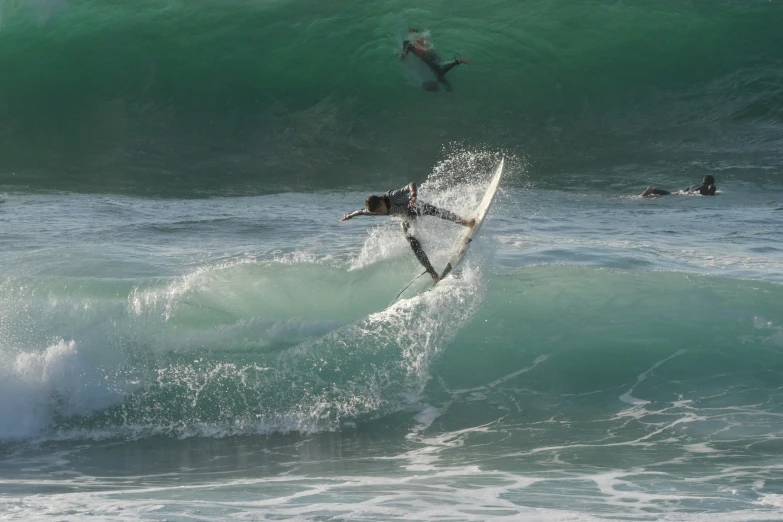 a surfer rides on a wave as others swim in the water