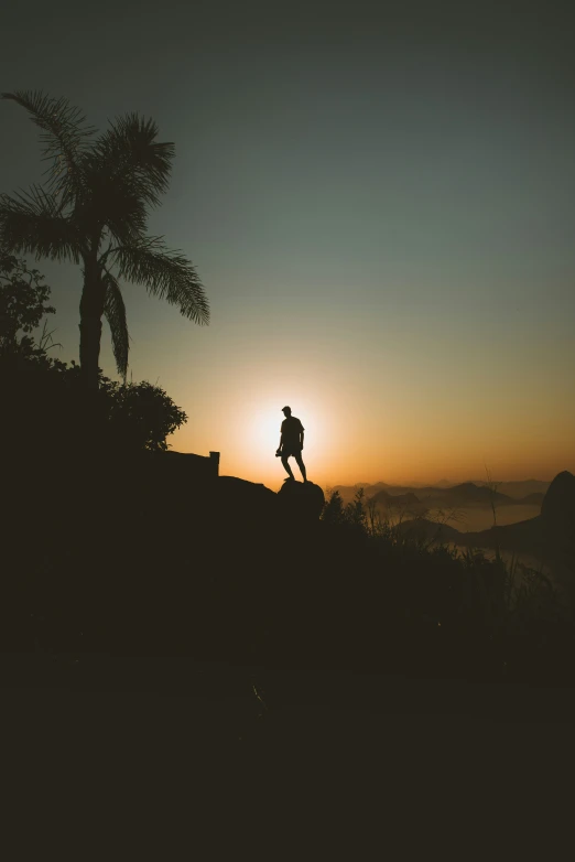 the silhouette of a man on top of a hill