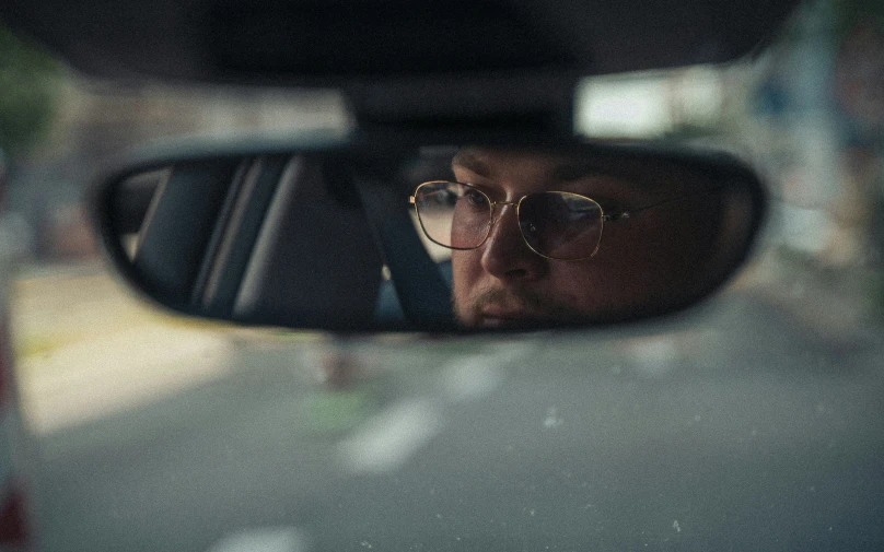 a man in glasses sitting inside of a car