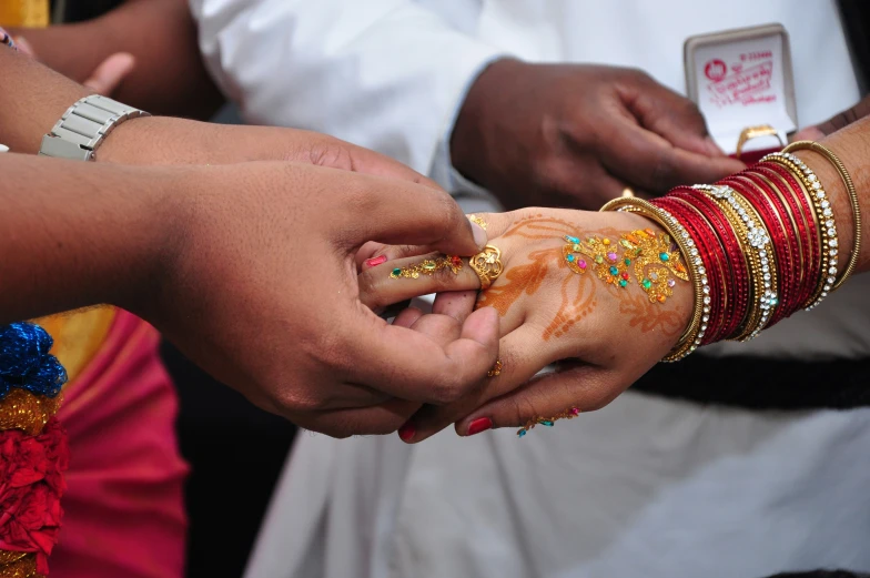 people wearing bangles and celets with colorful designs on their hands