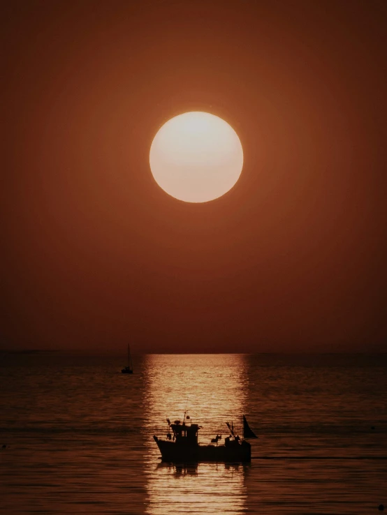 a boat floating under the moon in the middle of a large body of water