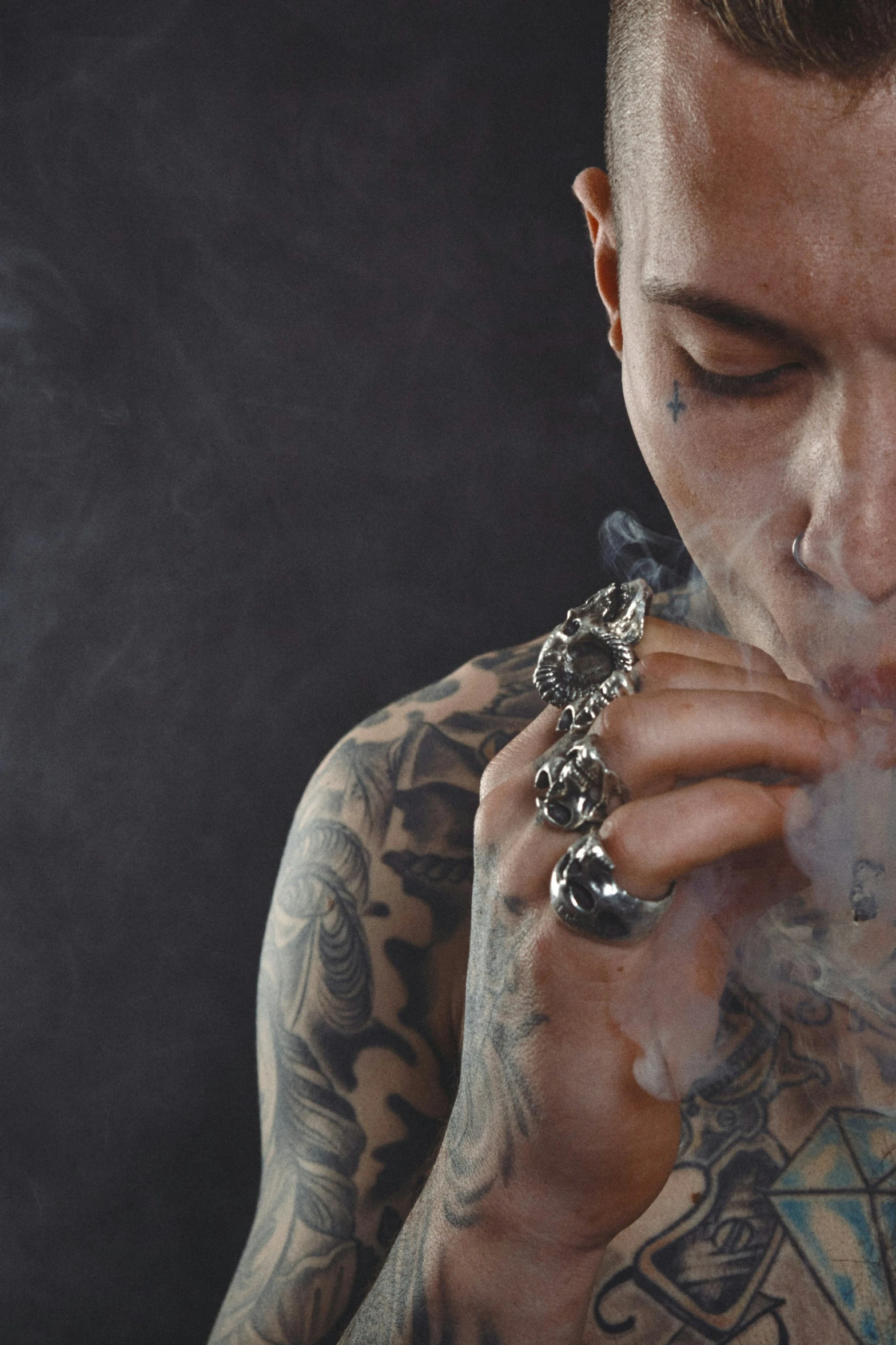 a man with tattoos holding up some smoke